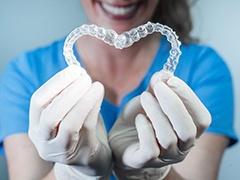 dentist holding two Invisalign aligners in the shape of a heart 