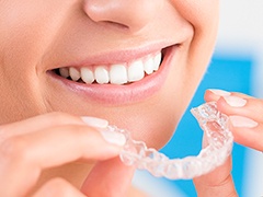 Closeup of smiling patient holding Invisalign tray