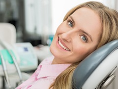 Smiling woman in dental exam chair for crown lengthening treatment