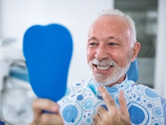 Senior dental patient looking at smile after all on 4 dental implant tooth replacement
