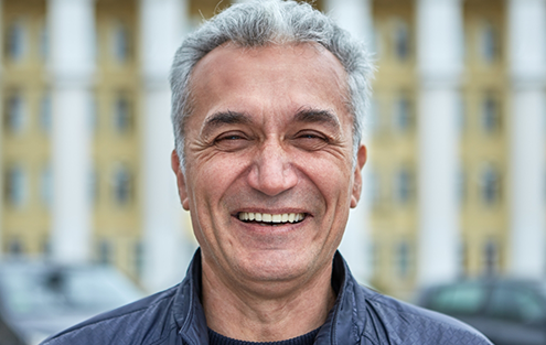 Older man in gray collared shirt smiling