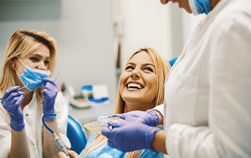 Woman in dental chair grinning at her dentist