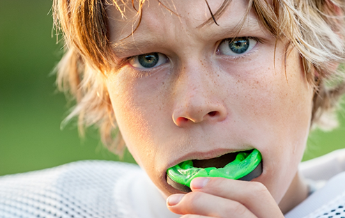 Boy placing a green sportsguard into his mouth