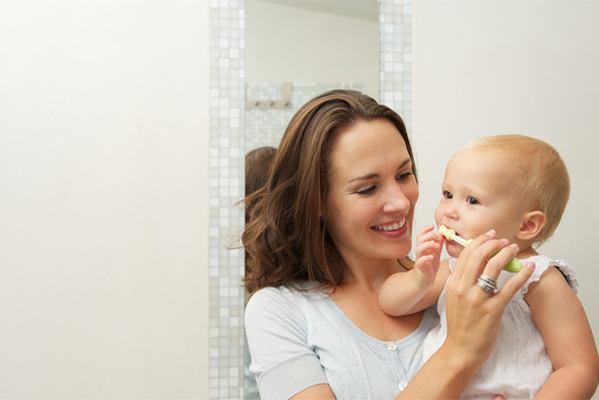 woman holding baby brushing teeth