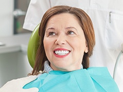 Smiling older woman in dental chair after oral cancer screening