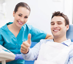 Smiling man in dental chair giving thumbs up 