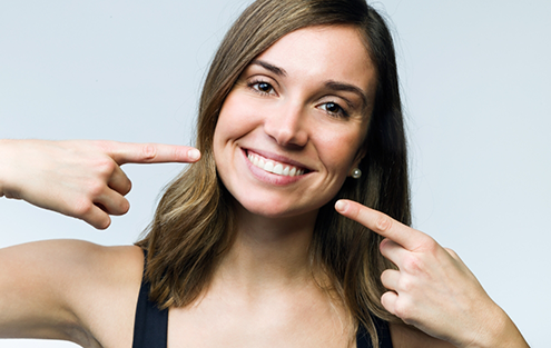 Brunette woman pointing to her smile