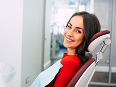 Woman smiling in dental chair wearing red shirt