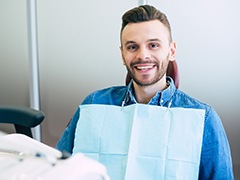 Man in dental chair smiling with denim shirt on