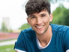 Young man smiling outside after Invisalign treatment