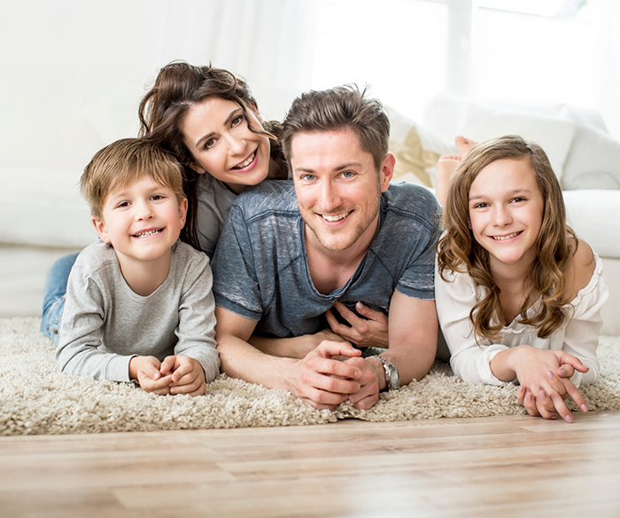 Family of four smiling in living room after seeing Delta Dental dentist in Torrance