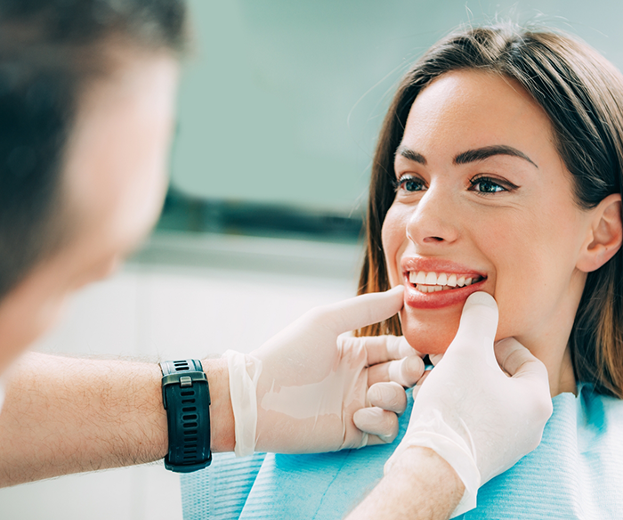 Dentist examining a patients smile after dental implant failure and salvage in Torrance