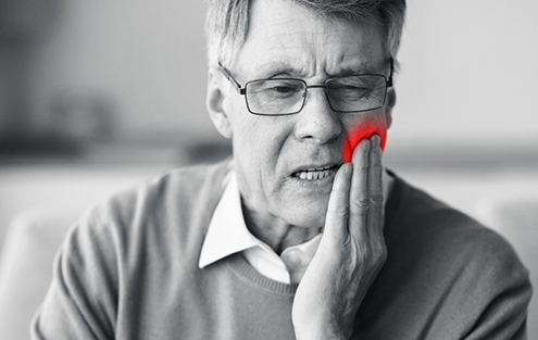Man holding the side of his jaw in pain