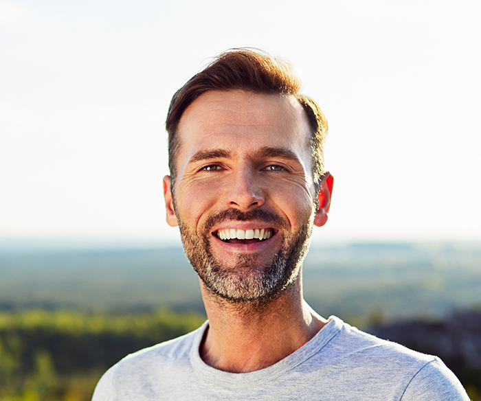 Man smiling outdoors with dental implants in Torrance