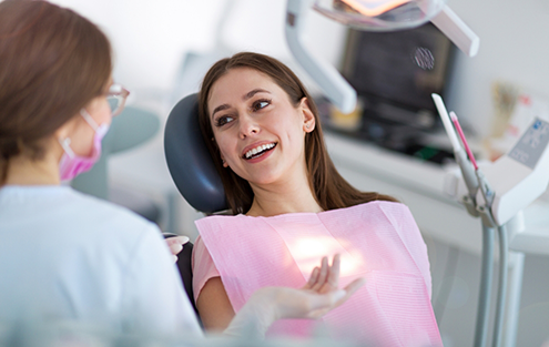 Woman in dental chair talking with her dentist about the cost of dental implants