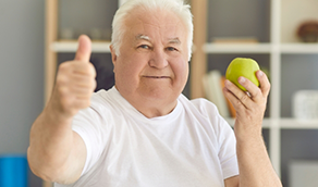 Man holding an apple and giving a thumbs up