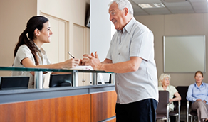 Senior man talking to dental office receptionist