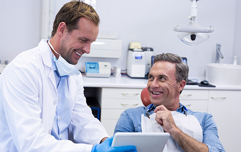 Smiling dentist showing a tablet to a patient