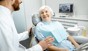 Senior woman in dental chair smiling at her dentist