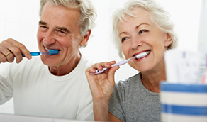 Senior man and woman brushing their teeth together