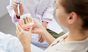 Dentist showing a model of a dental implant to a patient
