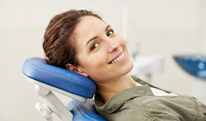 Woman leaning back in dental chair and smiling