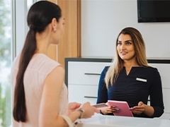 woman talking with dental team member at the front desk