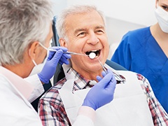 Senior man with denture receiving dental exam
