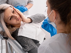 a woman holding her mouth and talking to her dentist