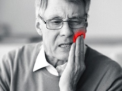 An older man holding his cheek in pain because of a failed dental implant in Torrance