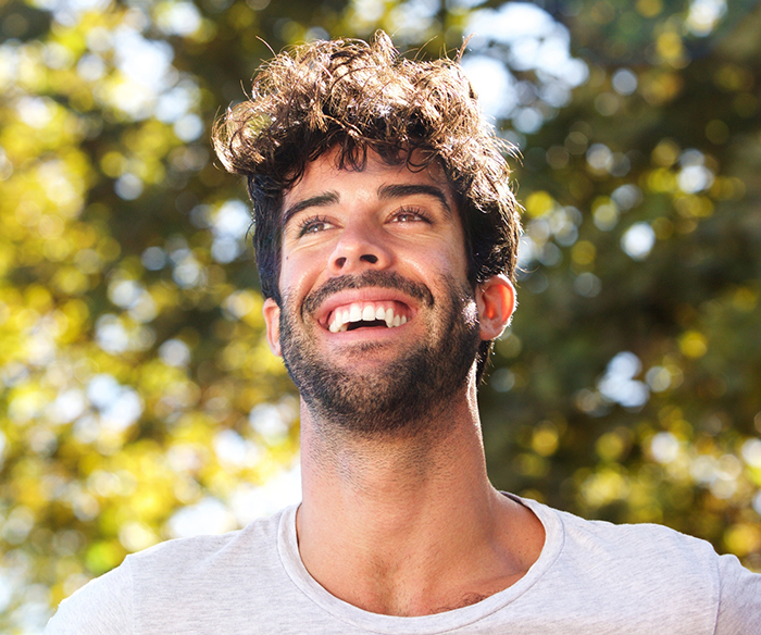 Young man smiling outdoors after full mouth reconstruction in Torrance