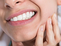 Closeup of patient in need of nightguard for teeth grinding holding jaw