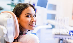 Smiling woman in dental chair looking over her shoulder