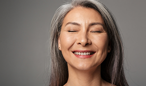 Woman with long gray hair smiling with eyes closed