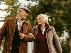 An older couple linking arms and going for a walk and appearing happy