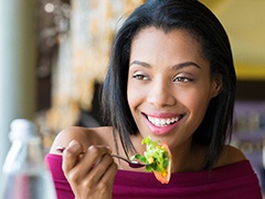 A young woman eating a salad and smiling in Torrance