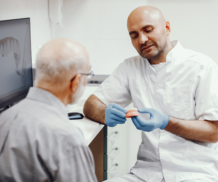 Dentist showing a patient a model of implant dentures in Torrance