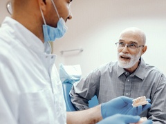 senior man asking his dentist about implant dentures