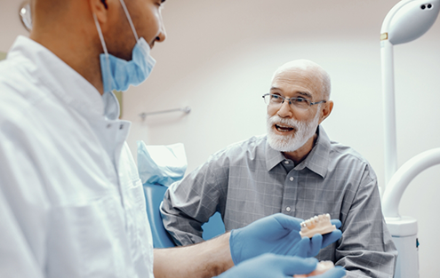 Senior man talking to his dentist about implant dentures