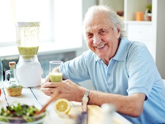 Older man with dental implants in Torrance drinking a smoothie