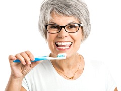 Older woman holding a toothbrush and smiling