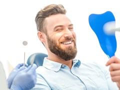 Happy patient admiring his new dental implant restorations