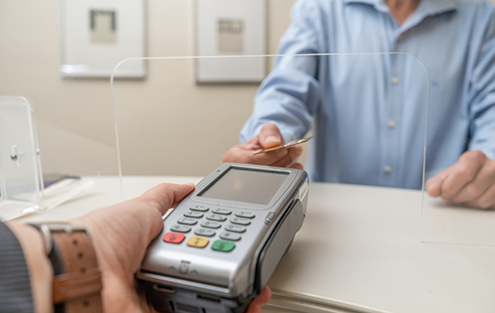 Man swiping his payment card at dental office front desk