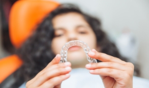 Teen girl looking at clear aligner in treatment chair