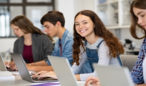 Teen girl smiling while working on computer in classroom