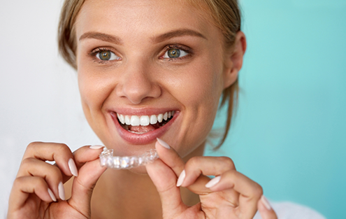 Woman holding an Invisalign aligner near her smile