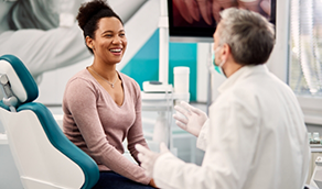 Woman in dental chair laughing with her dentist