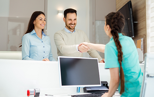 Dental team member shaking hands with a patient at front desk