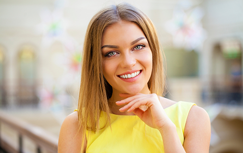 Woman smiling in yellow sleeveless blouse