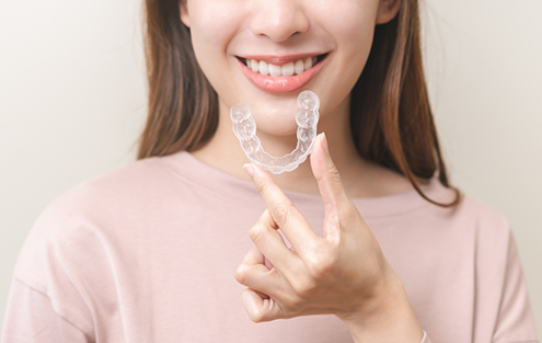 Smiling woman holding an Invisalign tray